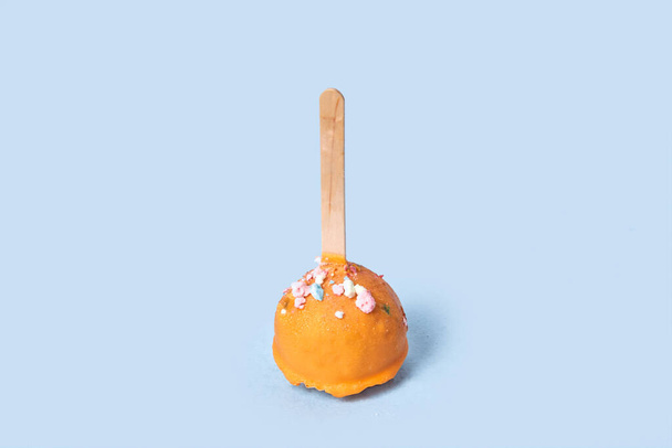 Chocolate dessert in orange glaze. Round pastry on a wooden stick. - Фото, изображение