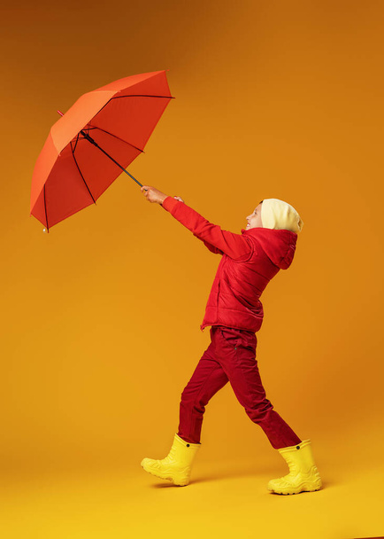 Emotionele Grappige Happy Boy, Tiener, Gaat En Lachen In De Herfst Kleding Met Een Rode Paraplu Op Gele Kleur Achtergrond - Foto, afbeelding