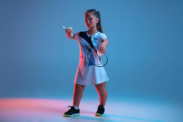 Beautiful dwarf woman practicing in badminton isolated on blue background in neon light - Foto, Bild
