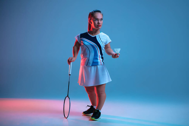 Beautiful dwarf woman practicing in badminton isolated on blue background in neon light - Foto, imagen