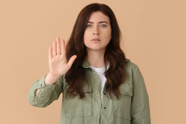 Young deaf mute woman using sign language on color background - Foto, imagen