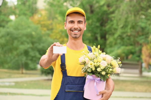 Entrega hombre con hermosas flores y tarjeta de visita al aire libre - Foto, Imagen