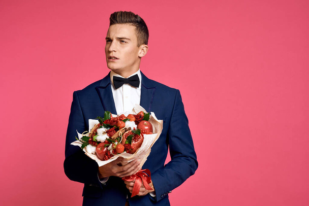romantic man with bouquet of flowers and in bow tie on pink background cropped view - Fotografie, Obrázek