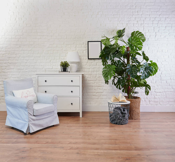 Декоративний білий шафа і синє крісло, ваза рослинного і ковдрового стилю, фон цегляної стіни
. - Фото, зображення