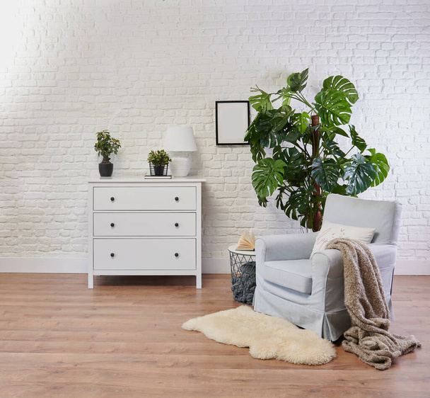 Decorative white cabinet and blue armchair, vase of plant and blanket style, brick wall background. - Photo, Image