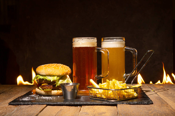 Tasty dinner with two beer glasses, hamburger and fries.  - Foto, Imagen
