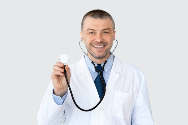 Портрет зрілого лікаря, який посміхається і вказує в просторі копіювання
 - Фото, зображення