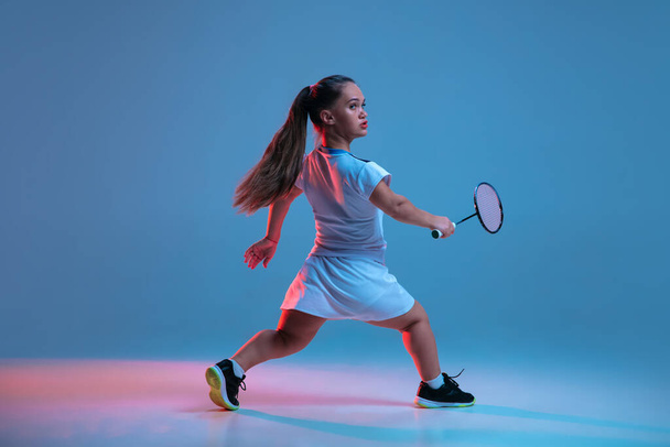 Beautiful dwarf woman practicing in badminton isolated on blue background in neon light - Foto, Imagem