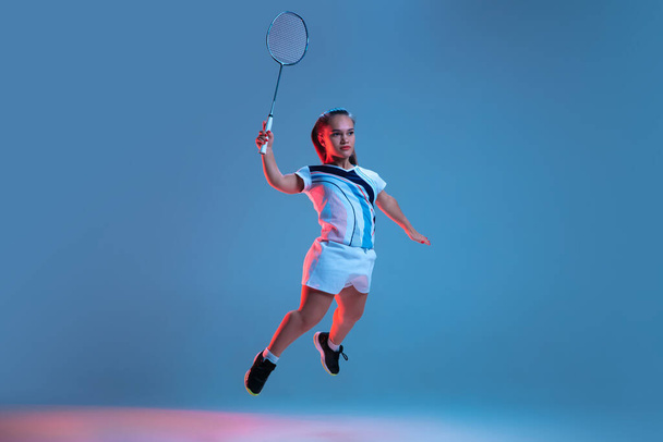 Beautiful dwarf woman practicing in badminton isolated on blue background in neon light - Photo, image