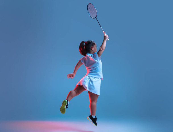 Beautiful dwarf woman practicing in badminton isolated on blue background in neon light - Foto, Bild