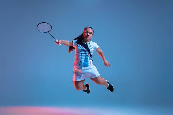 Beautiful dwarf woman practicing in badminton isolated on blue background in neon light - Foto, immagini