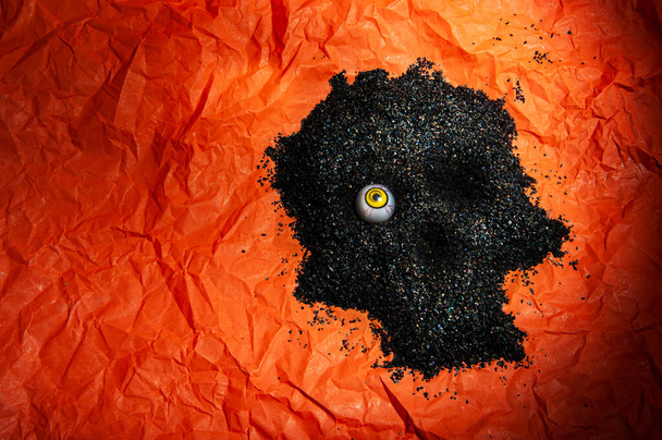 calavera de carbón sobre un fondo de papel naranja arrugado - Foto, Imagen