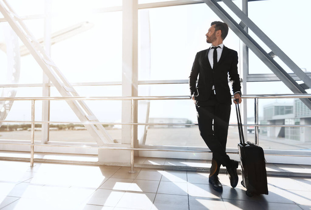 Menestyvä liikemies seisoo ikkunan vieressä lentokentällä - Valokuva, kuva