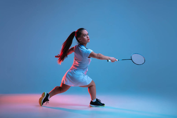 Beautiful dwarf woman practicing in badminton isolated on blue background in neon light - Фото, изображение