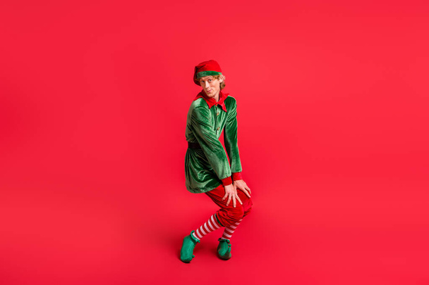 Kırmızı renkli arka planda izole edilmiş yeşil başlık giyen komik elfin tam boy fotoğrafı. - Fotoğraf, Görsel