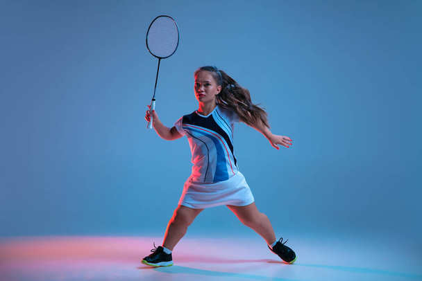 Beautiful dwarf woman practicing in badminton isolated on blue background in neon light - 写真・画像