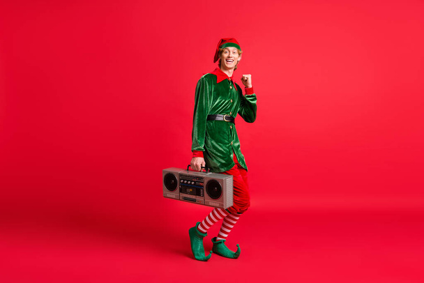 Full length photo of crazy elf hold boom box raise fists x-mas christmas event concept isolated on red color background - Fotó, kép