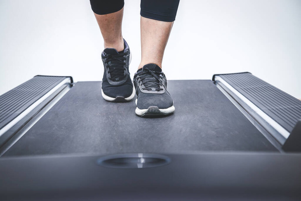 Edzőcipőt viselő nők az elektromos futópadon fitnessz órán. - Fotó, kép