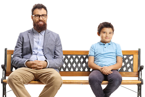 Bearded man smiling and sitting on a bench next to a boy isolated on white background - Photo, image
