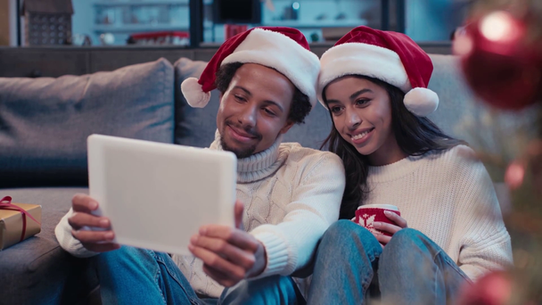 šťastný africký americký pár mává rukama a při pohledu na digitální tablet  - Záběry, video