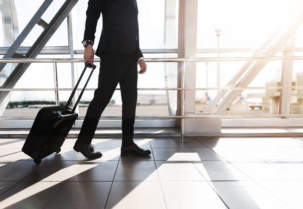 Cultivado de hombre de negocios caminando por el aeropuerto con maleta - Foto, Imagen