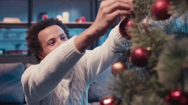 Χαρούμενος Αφροαμερικάνος που στολίζει χριστουγεννιάτικο δέντρο - Πλάνα, βίντεο