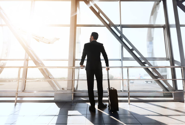 Back view of businessman standing next to window at airport - Photo, Image