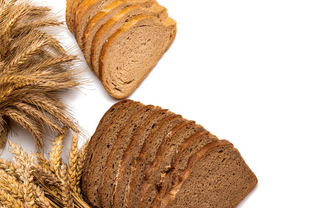 Lahodný chleba. Čerstvý bochník rustikálního tradičního chleba s pšeničným zrnitým uchem nebo špičatou rostlinou izolovanou na bílém pozadí. Žitná pekárna s křupavými bochníky a drobky. Domácí pečení - Fotografie, Obrázek