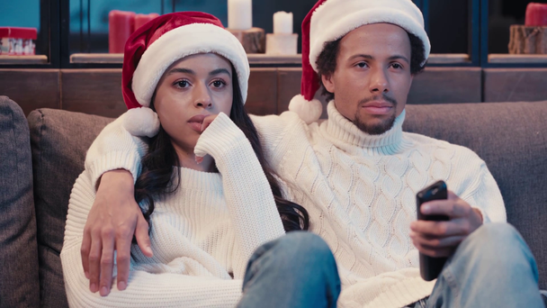African american man watching movie with scared woman in santa hat - Footage, Video