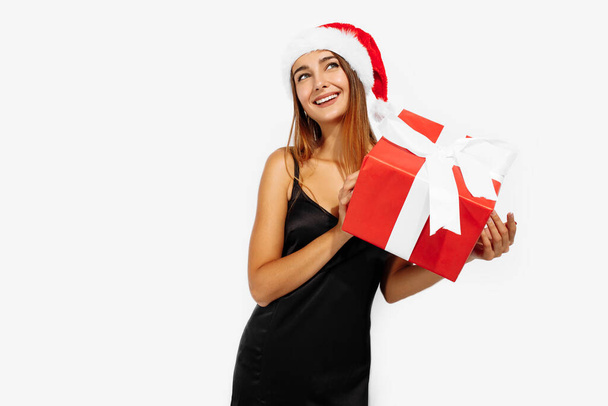 Excited young woman in christmas red hat with gift box on white background - Foto, Imagem