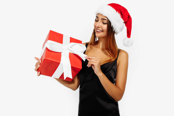 Excited young woman in christmas red hat with gift box on white background - Φωτογραφία, εικόνα