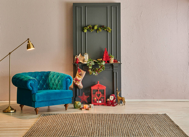 Різдвяна вітальня перед кам'яною стіною і сірий класичний камін, ялинка, золота лампа і синє крісло
. - Фото, зображення