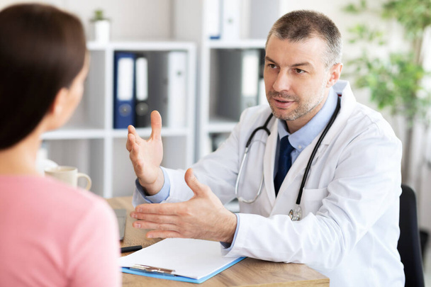 Male experienced doctor talking to his patient - Fotoğraf, Görsel