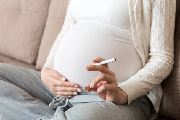 Terhes nő cigarettával otthon. anyai dohányzás fogalma. - Fotó, kép