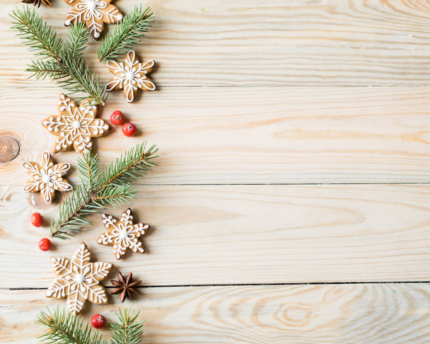 Mézeskalács sütik hópelyhek fenyőágakkal és bogyókkal fából készült háttérrel. Karácsonyi, újévi és téli ünnepek koncepció. Felülnézet, vízszintes tájolás, másolótér - Fotó, kép