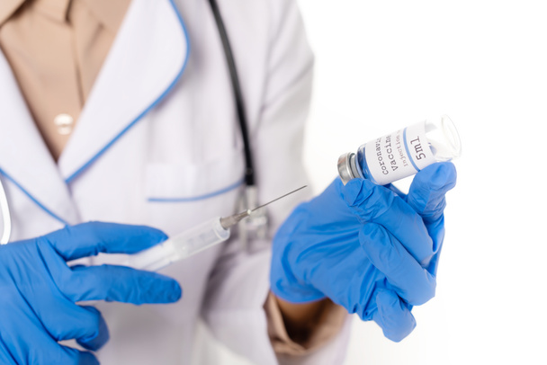 Vista recortada del médico con guantes de látex que sostienen el frasco con la vacuna contra el coronavirus y la jeringa aisladas en blanco - Foto, imagen