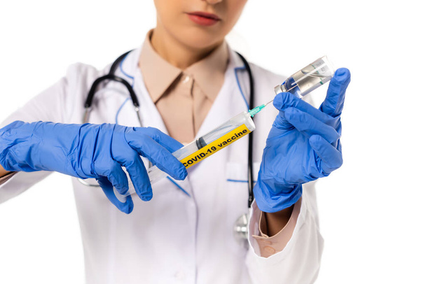 Cropped view of doctor picking up vaccine in syringe with covid-19 lettering isolated on white - Fotografie, Obrázek
