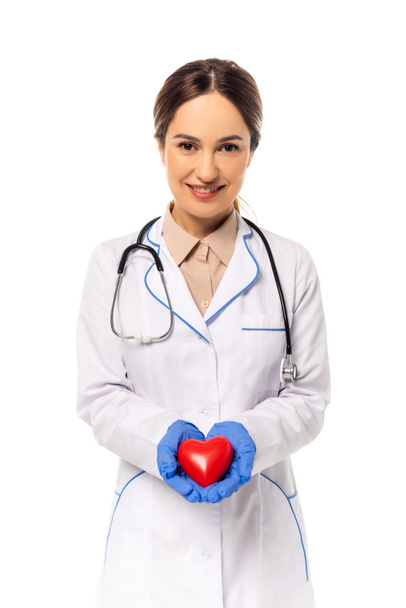 Smiling doctor in latex gloves holding red heart isolated on white - Foto, Bild