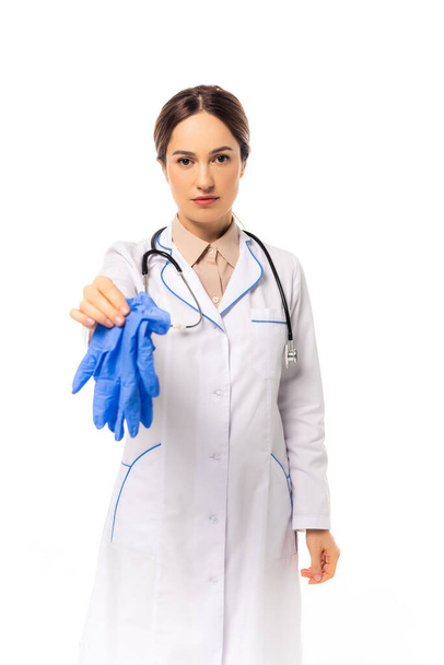 Arzt mit Stethoskop hält Latexhandschuhe isoliert auf weiß - Foto, Bild