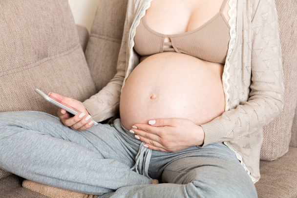 Ragazza incinta caucasica utilizzando il cellulare, a riposo sul letto a casa. - Foto, immagini