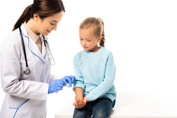 Smiling pediatrician holding patch near hand of kid isolated on white - Valokuva, kuva