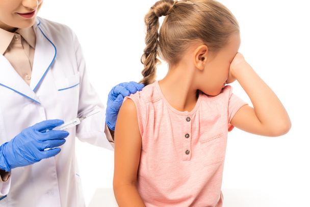 Pediatra segurando seringa perto de criança assustada isolada em branco - Foto, Imagem