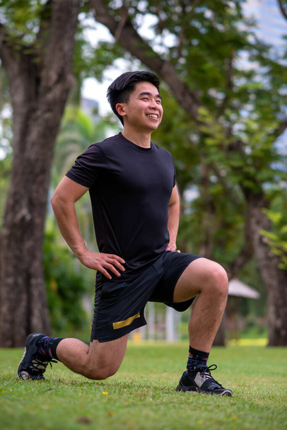 ázsiai fiatal férfi do lunge gyakorlat a parkban - Fotó, kép