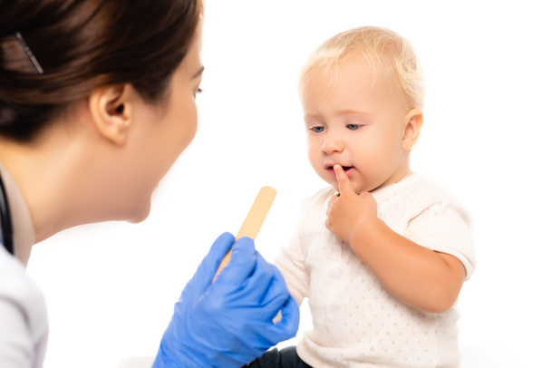 Concentration sélective du pédiatre tenant bâton près de tout-petit garçon isolé sur blanc - Photo, image