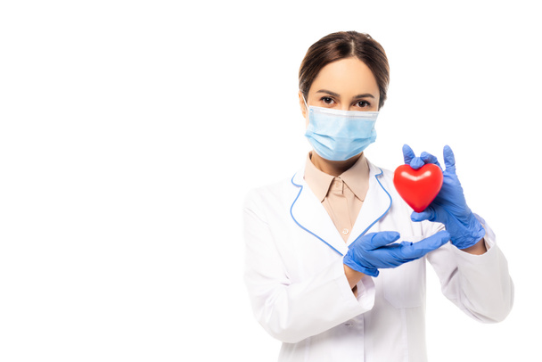 Doctor in medical mask and latex gloves holding heart isolated on white - Valokuva, kuva
