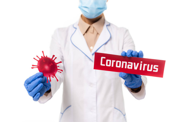 Cropped view of doctor holding card with coronavirus lettering and bacteria isolated on white - Foto, Imagem