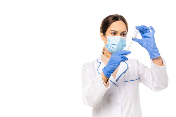 Doctor in medical mask picking up coronavirus vaccine in syringe isolated on white - Fotografie, Obrázek