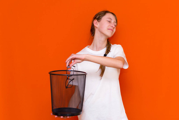 Крупным планом улыбается спокойная серьезная молодая девушка выбросить свои очки в мусорное ведро - Фото, изображение