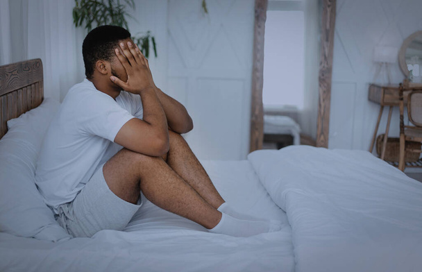 Uomo nero che soffre mal di testa Dolore seduto a letto all'aperto - Foto, immagini