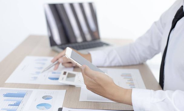 Przedsiębiorcy finansowi używają laptopa i smartfona do analizy strategii marketingowych i danych nieruchomości w celu obniżenia podatków od przedsiębiorstw dla swoich klientów, Koncepcja księgowości i podatków. - Zdjęcie, obraz